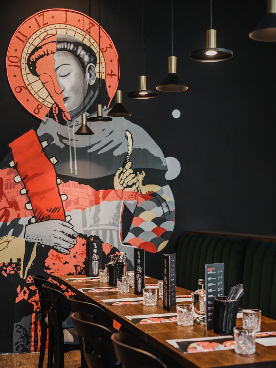 Wnętrze restauracji Żeberka z kolorowym muralem i nakrytymi stołami.