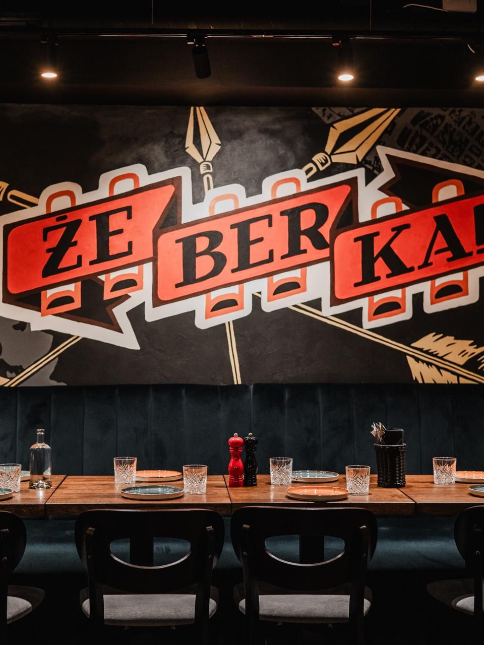 Wnętrze restauracji Żeberka z muralem i nakrytymi stołami.